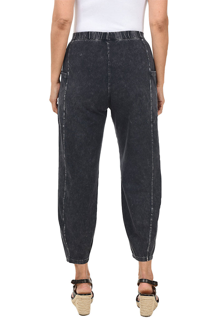 A back shot of a model wearing a black mineral wash pull-on ankle pants with an elasticized waistband, dual side pockets, and tapered leg design.