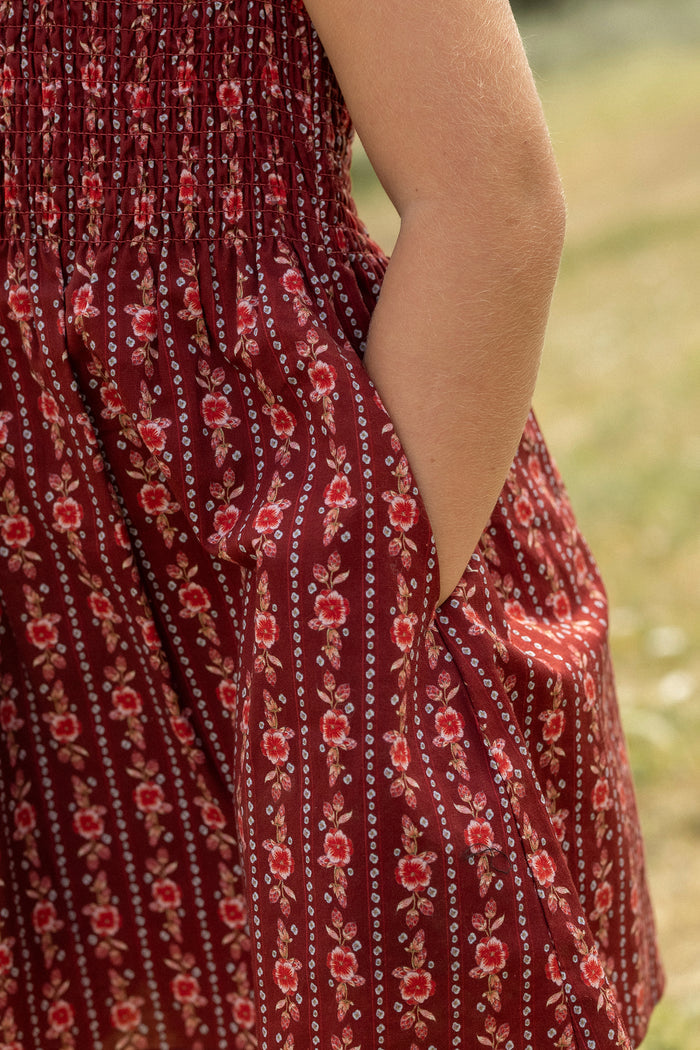 A close-up of a person’s arm and hand in the pocket of the Ivy City Co Mini Ana Dress in Sequoia Felicity Floral, captured outdoors in natural light.