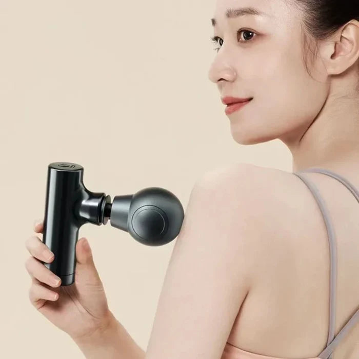 Mini massage gun in use on shoulder for muscle recovery