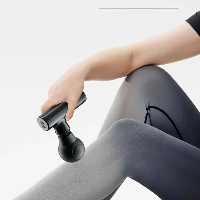 Mini massage gun in use on leg muscle after workout