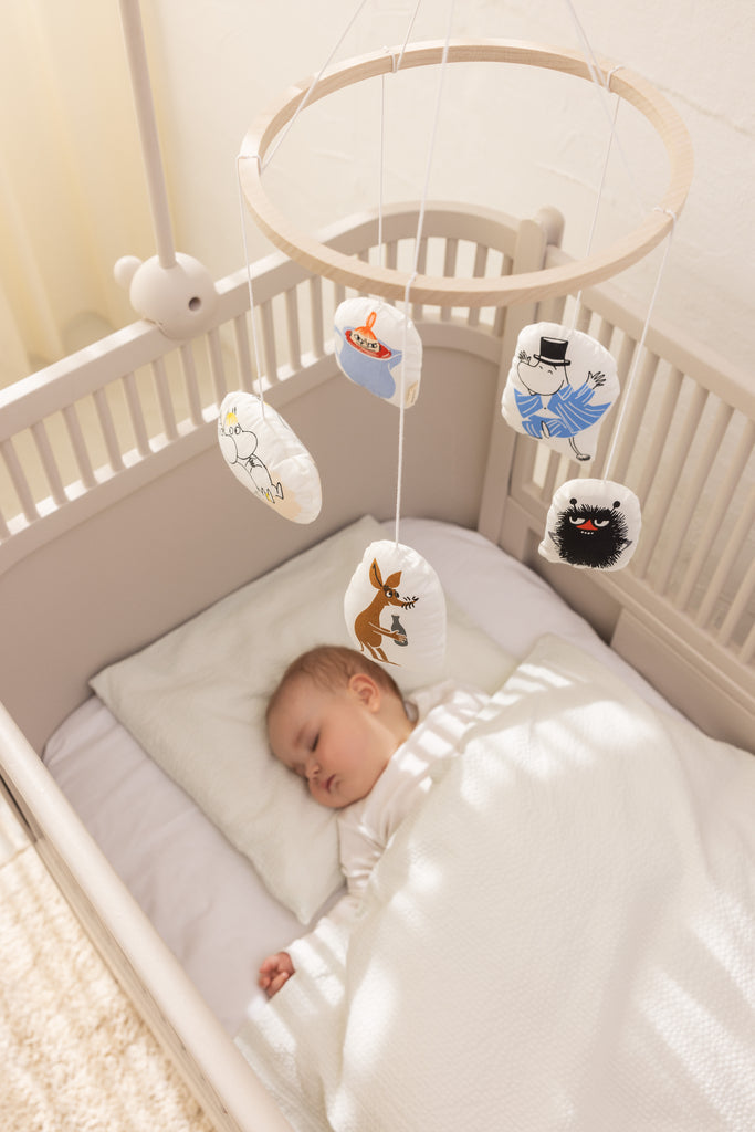 Babymobil til tremmeseng med hængende Moomin-figurer over babys seng.