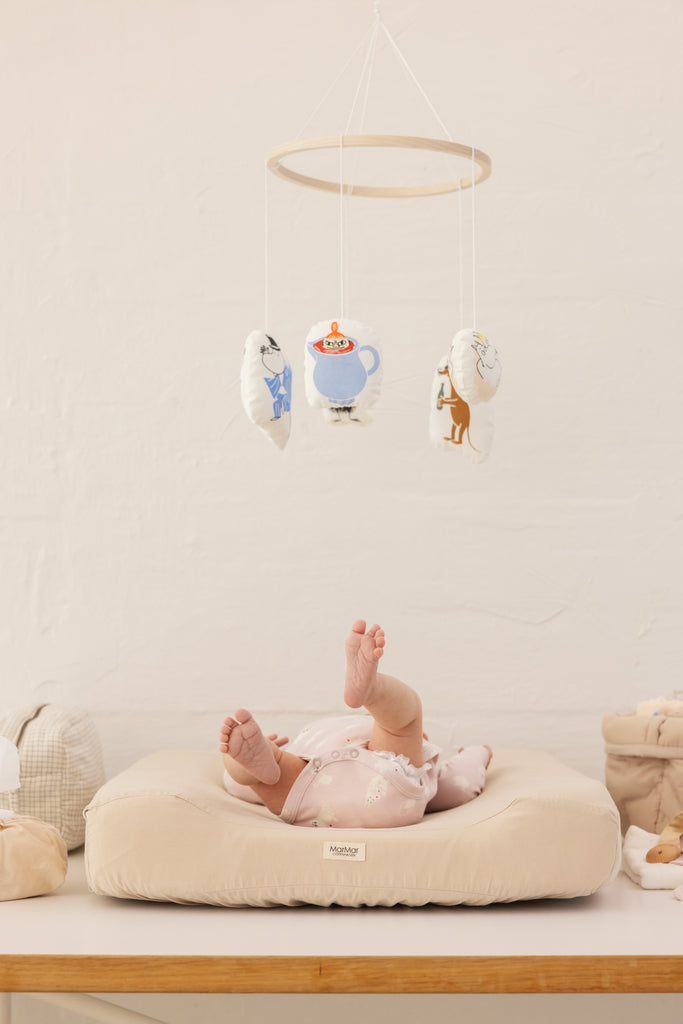Babymobil med Moomin-figurer ophængt i ring over babypude.