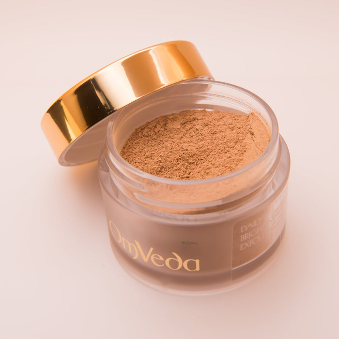 OmVeda exfoliant jar open, showing fine beige powder