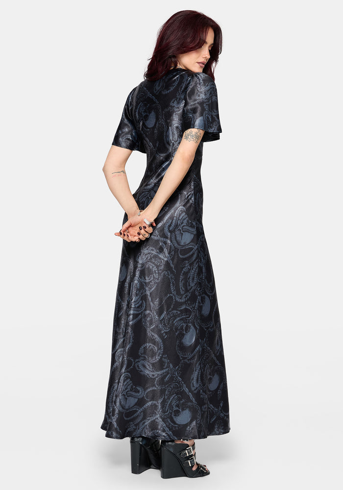 Woman wearing a black maxi satin snake printed dress on a white background