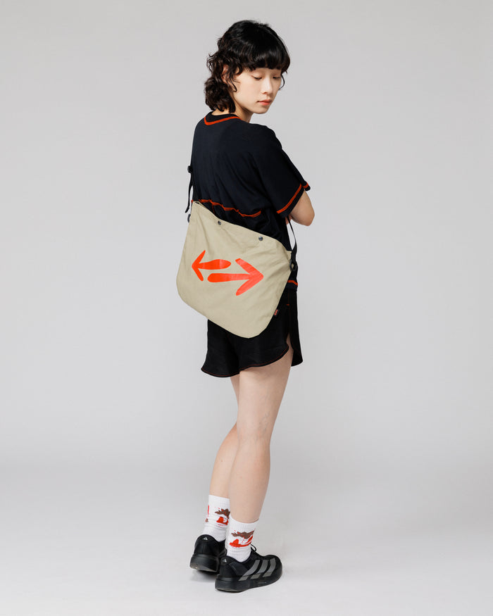 Outnback Musette in stone worn across the back, full-body rear view on model showing double arrow logo