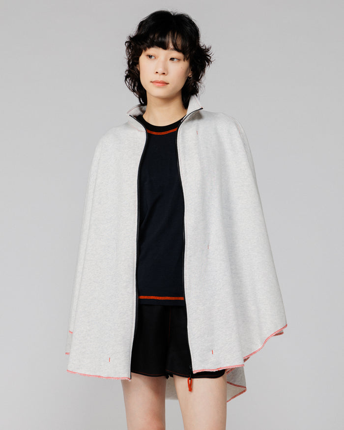 Cropped view of the Outnback Recovery Cape in marl grey worn open over a black tee and shorts