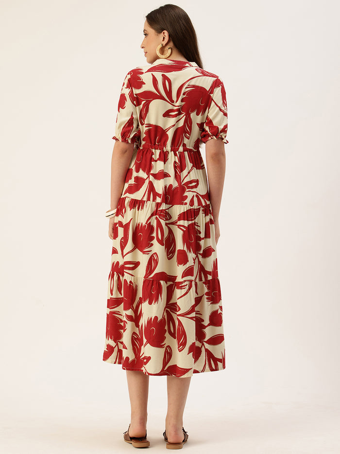 Woman in a red and white floral dress holding a brown handbag, standing next to a small wooden table with flowers on a beige background. Red Floral Printed Puff Sleeves Midi Dress, midi dress, dress, women’s western wear, party wear dress, casual wear dress