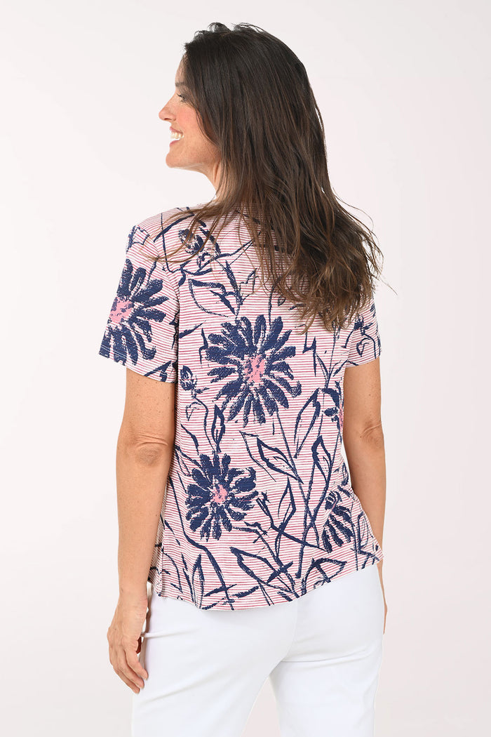 Woman wearing a pink and blue daisy print tee.