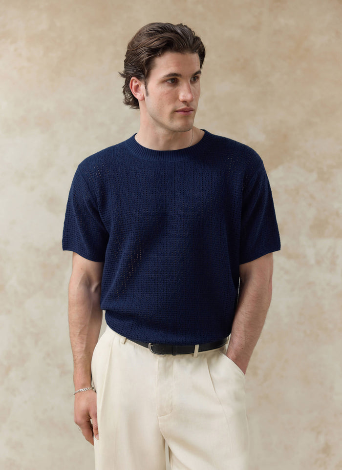The navy Percival Siena Knitted T Shirt, featuring a textured open-work cotton knit, styled on a model.