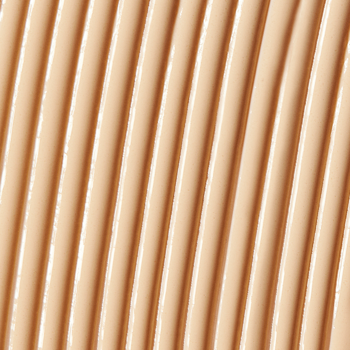 Close-up texture of a smooth, creamy beige skincare serum applied in parallel lines, representing Solarglow™ Mineral Serum Sunscreen | NUDA for a radiant, protective finish.