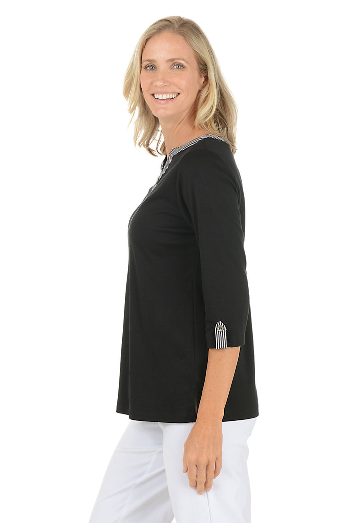 Woman wearing a black long-sleeve top with a white background. Side shot.