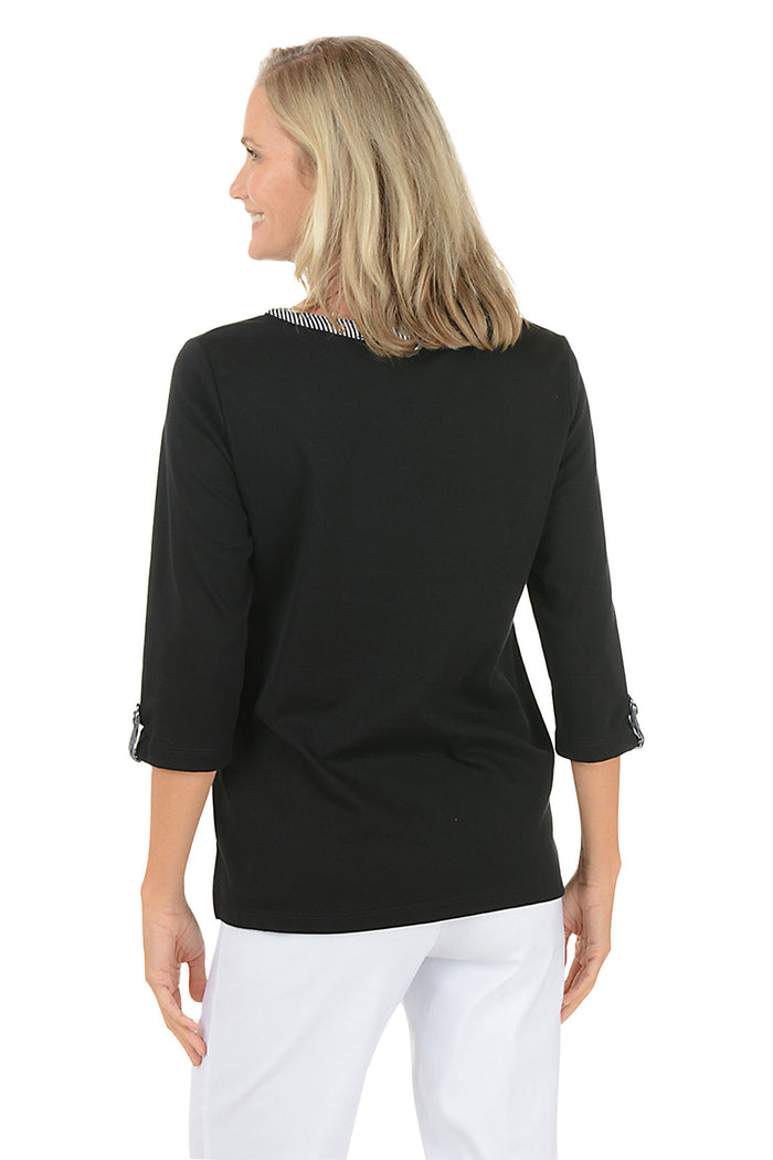 Woman wearing a black long-sleeve top with a white background. Back shot.