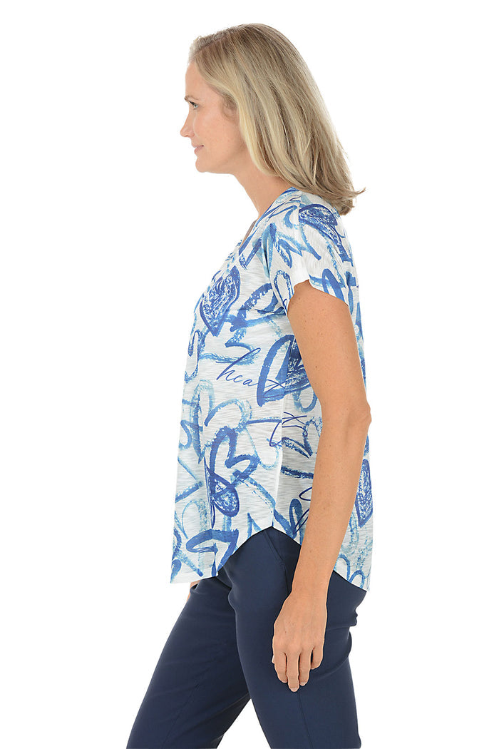 A woman wearing a blue and white short sleeve v-neck shirt with a heart design. Side shot.