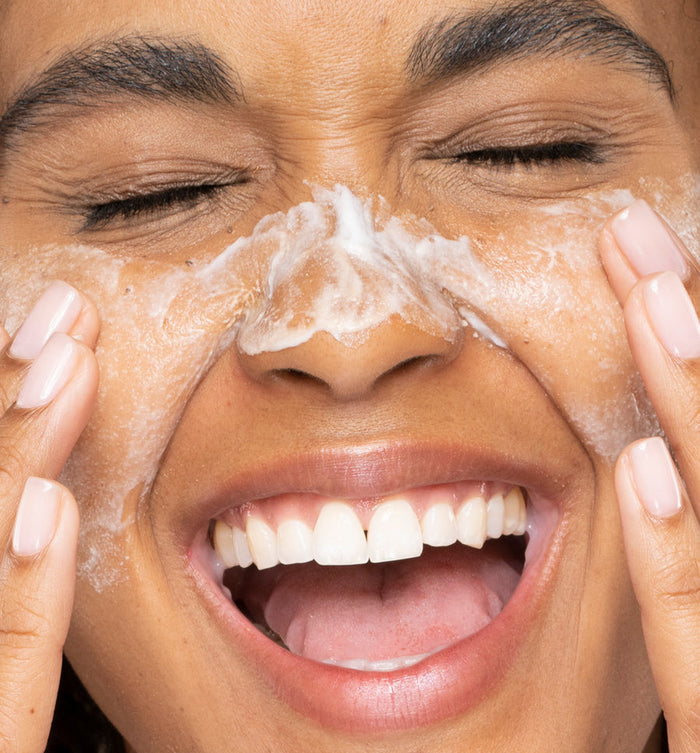 Close-up of a joyful person gently applying Timescape™ Micromazing™ 2-Minute Renewing Face Polish | Farmhouse Fresh on their nose and cheeks, highlighting skincare and self-care wellness.