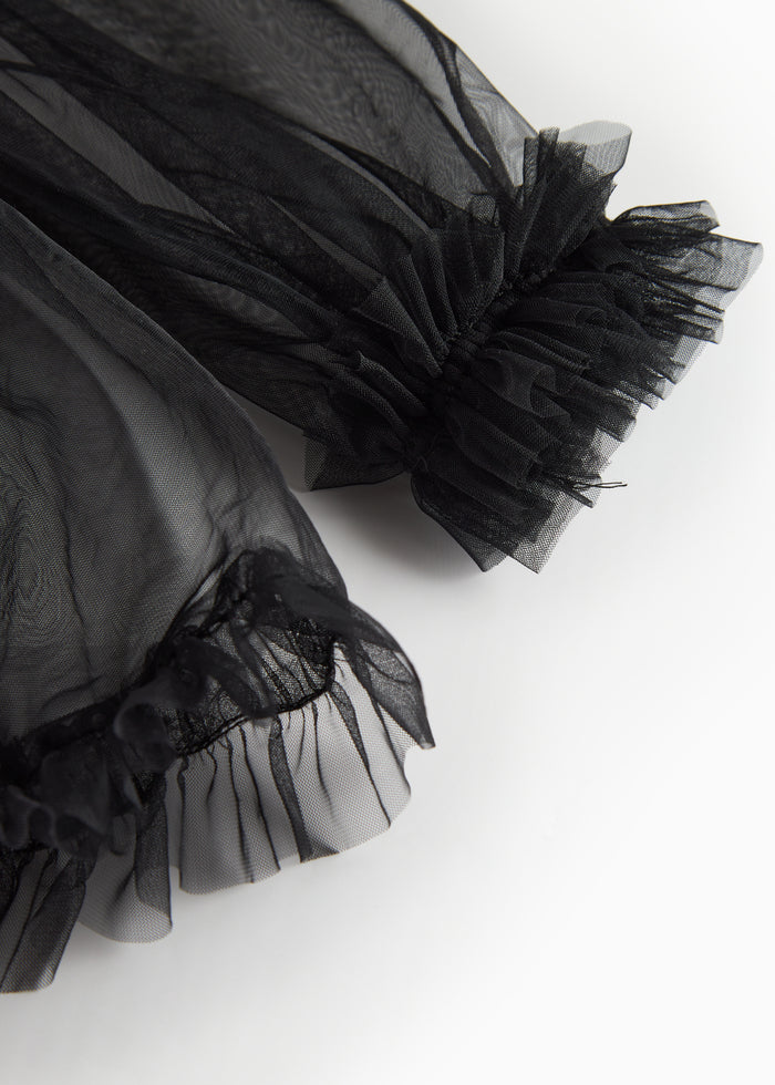 Detail of black tulle blouse with ruffles at sleeve hem