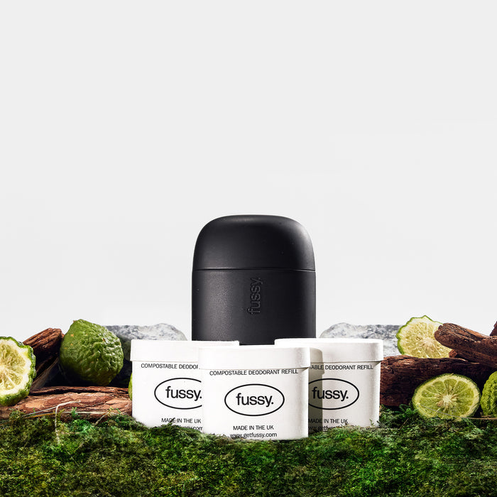 Fussy's Wilderness Deodorant Starter Pack with Midnight Case set against a backdrop of cedarwood, green bergamo and vetiver